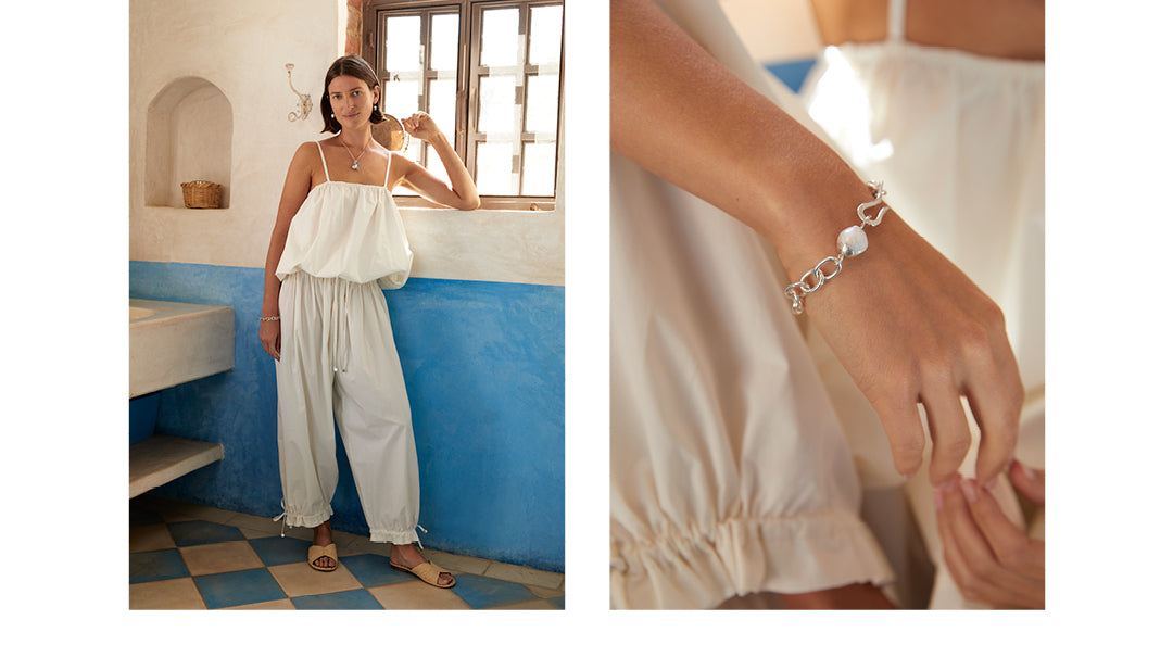Editorial spread of woman wearing a white bubble tank paired with white pants. On the opposite side is a closeup of a silver chain bracelet with pearl and hook detailing.